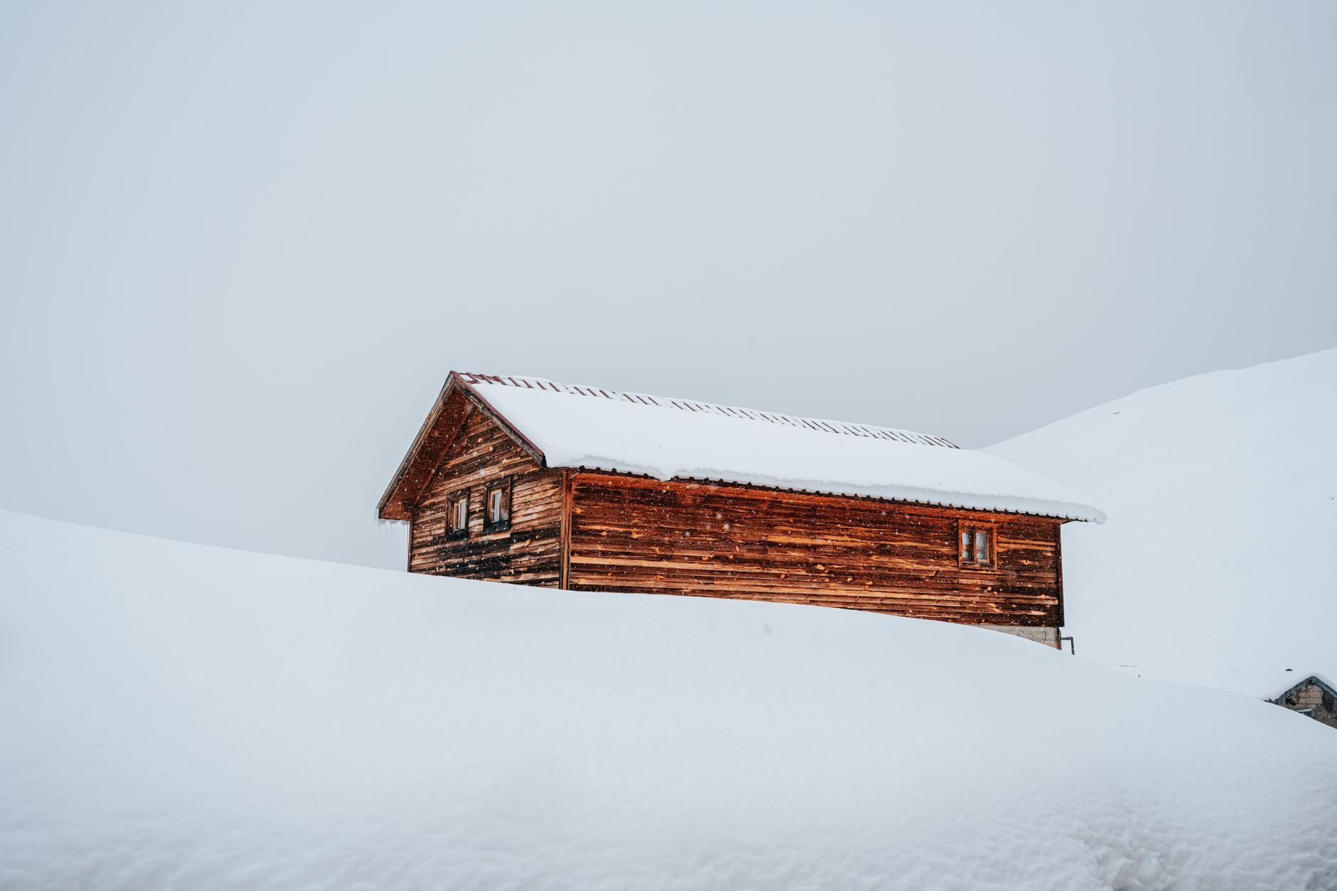 Grange d'alpage enfouie sous la neige, ciel blanc