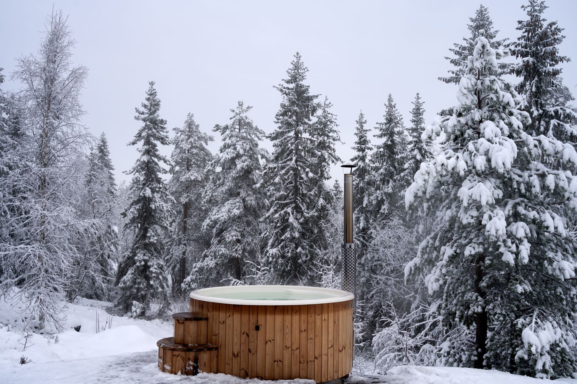 Bain nordique en bois dans une forêt enneigée