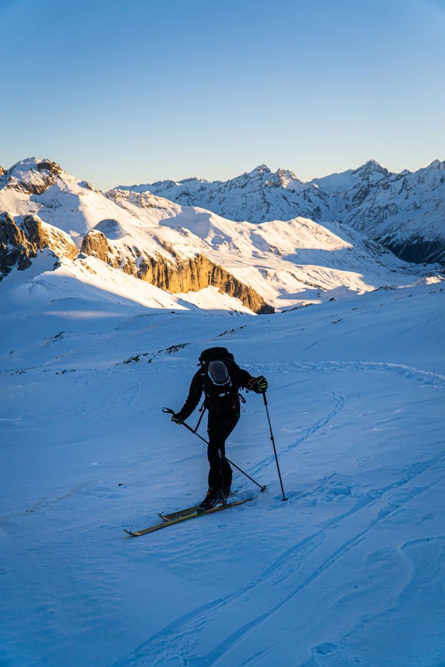 Skieur de randonnée à l'aube sur une pente vierge